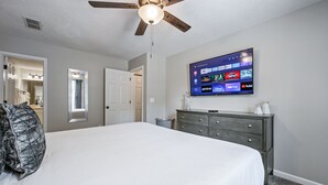 A bedroom with a large bed, a ceiling fan, a TV mounted on the wall displaying streaming services, and a dresser with drawers. - Superb For Traveling Workers Near Cartersville (Cartersville)