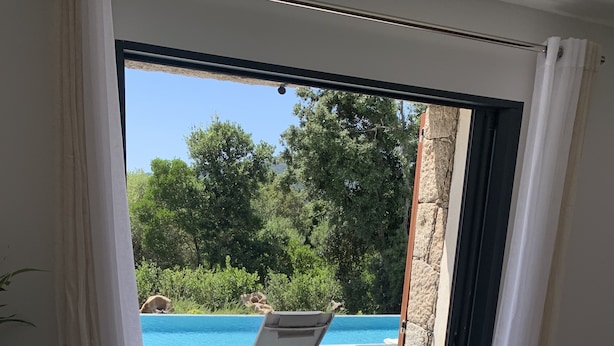 A modern room with a view of a swimming pool, a chair, and a small table.