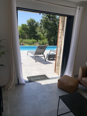 Quarto moderno com vista para uma piscina, uma cadeira e uma pequena mesa.