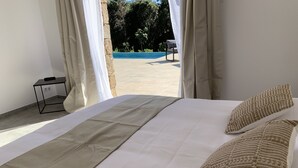 A bedroom with a bed, a nightstand, and a view of a swimming pool.