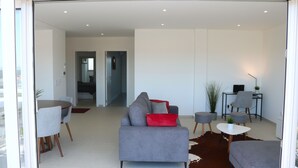 A modern living room with a grey sofa, red cushions, a small round table, and a cowhide rug. - Nazaré Views I - Terrace, Pool & Sea View (Nazaré)