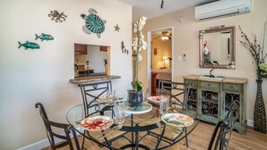 A dining area with a round table, chairs, and a decorative centerpiece. There is a mirror on the wall and a cabinet with glass doors.