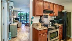 A modern kitchen with wooden cabinets, a black refrigerator, and a stainless steel oven.