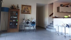 A spacious living area with a dining table and chairs, a kitchen area with a sink and countertop, and a staircase leading to another level. - Duplex 160 m2 (Saint Gilles les bains)