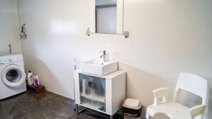 A bathroom with a washing machine, a sink with a mirror, and a white chair. - Homerez - House in Berrwiller (Berrwiller)