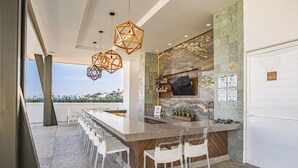 A modern kitchen with a large island, white chairs, and a stone backsplash. - CASA|AZUR – Distinctive Style with A View (Puerto Vallarta)