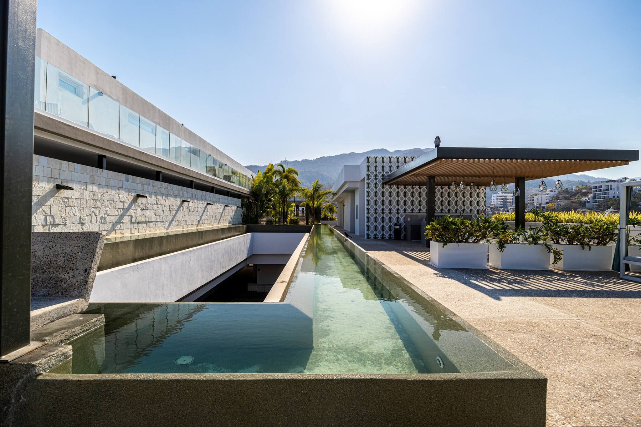 Ein Pool auf dem Dach mit klarem Wasser, umgeben von moderner Architektur und Pflanzen.