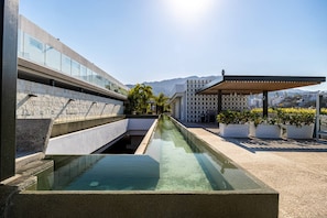 A rooftop pool with clear water, surrounded by modern architecture and plants.