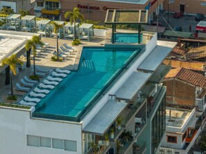A rooftop swimming pool with sun loungers and a view of the surrounding buildings.
