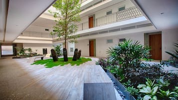 Ein mehrgeschossiges Gebäude mit Innenhof, Sitzgelegenheiten im Freien und verschiedenen Pflanzen.