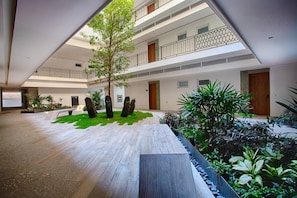 A multi-level building with a central courtyard, outdoor seating area, and a variety of plants.