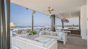 A modern outdoor lounge area with a pool, seating, and a view of the ocean. - CASA|AZUR – Distinctive Style with A View (Puerto Vallarta)