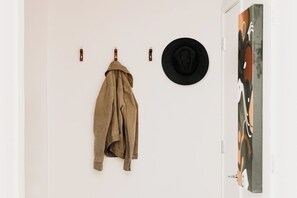 Ein Zimmer mit einem Mantel, der an einem Haken hängt, einem schwarzen Hut an der Wand und einer Tür mit einem Gemälde.