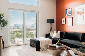 Ein modernes Wohnzimmer mit einer schwarzen Couch, einem Couchtisch und einem großen Fenster mit Blick auf die Stadt.