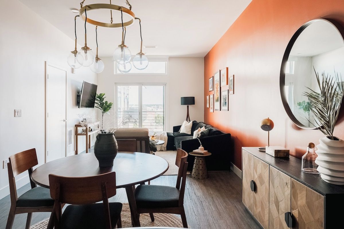 Ein modernes Wohnzimmer mit Essbereich, einem großen Spiegel und Blick auf die Stadt.