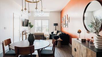Ein modernes Wohnzimmer mit Essbereich, einem großen Spiegel und Blick auf die Stadt.