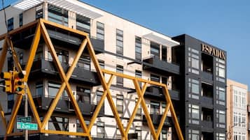 Een meerlaags gebouw met een opvallend 'ESPADIN'-bordes, een geometrisch gele constructie ervoor, en een heldere lucht.