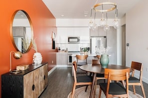 A modern kitchen with white cabinets, a microwave, and a stainless steel refrigerator.