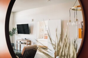 Ein modernes Wohnzimmer mit Flachbildfernseher, einem Holztisch, einem Sessel und einer Pflanze.