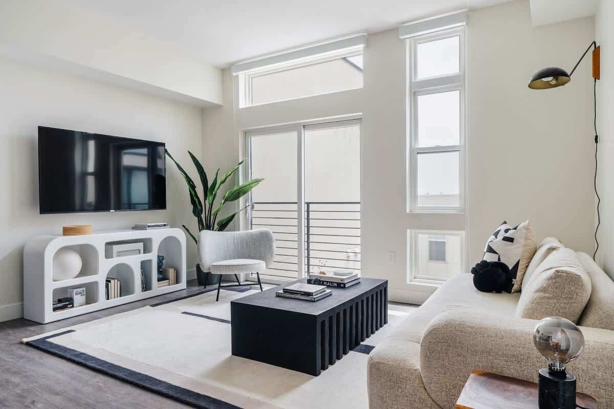 A modern living room with a flat-screen TV, a sofa, a coffee table, and a large window.