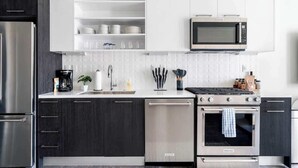 Una cocina moderna con armarios oscuros, un refrigerador de acero inoxidable, un microondas, un lavavajillas y una estufa.
