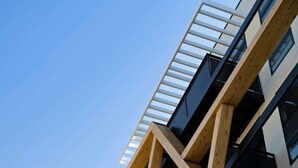 Un edificio de varios pisos con fachada geométrica, que cuenta con balcones y un cielo despejado al fondo.