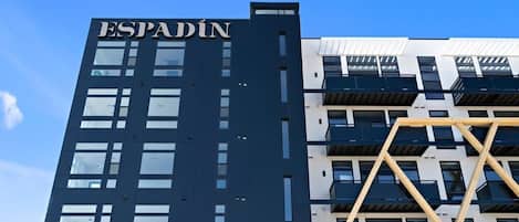 En moderne bygning med navnet "ESPADIN" på facaden, med et geometrisk design, altaner og store vinduer.