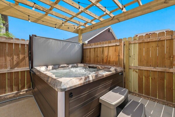 Un jacuzzi con una pérgola de madera encima, rodeado por una valla de madera.