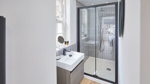 A modern bathroom with a glass shower enclosure, a white sink, and a mirror. - Host & Stay | Modern Industrial (Whitby)