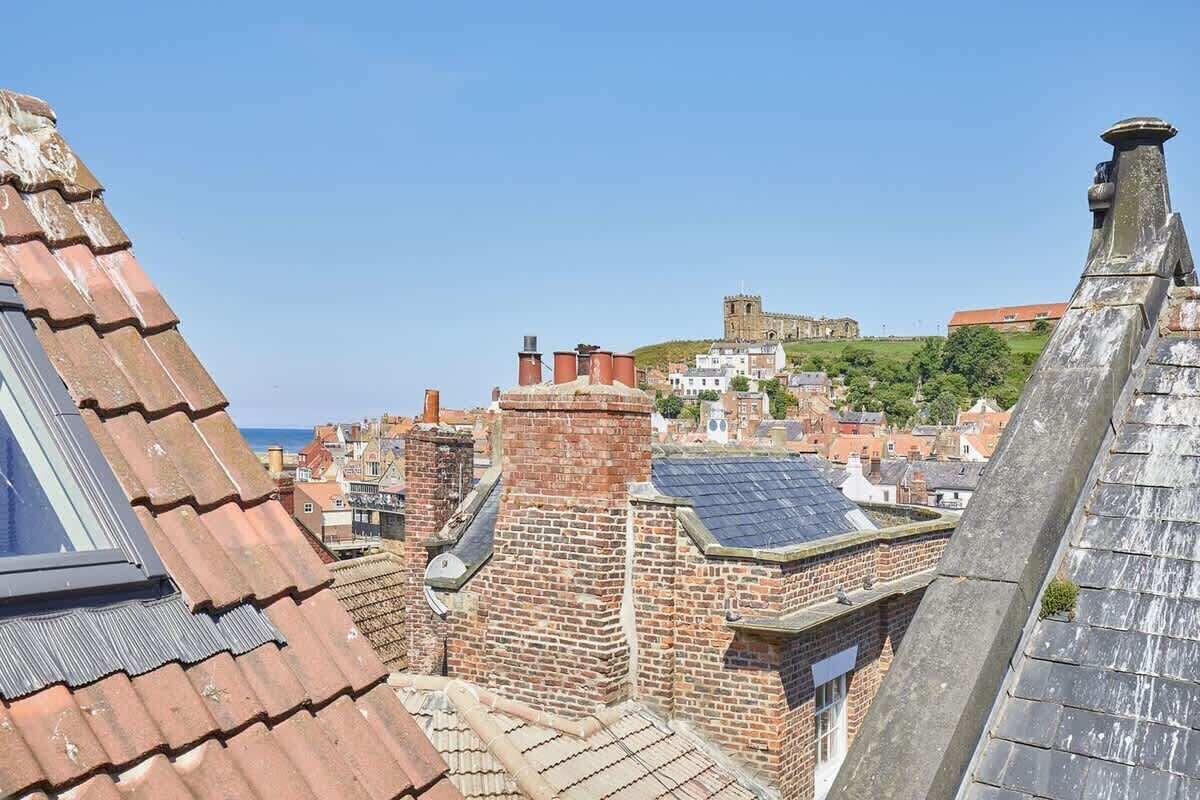 A view of a cityscape with historic buildings and a castle on a hill.