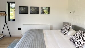 Ett modernt sovrum med en stor säng, ett fönster och tre inramade tavlor på väggen.