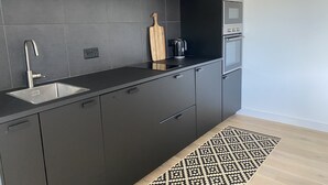 Ett modernt kök med mörka skåp, en diskho i rostfritt stål och en inbyggd ugn.