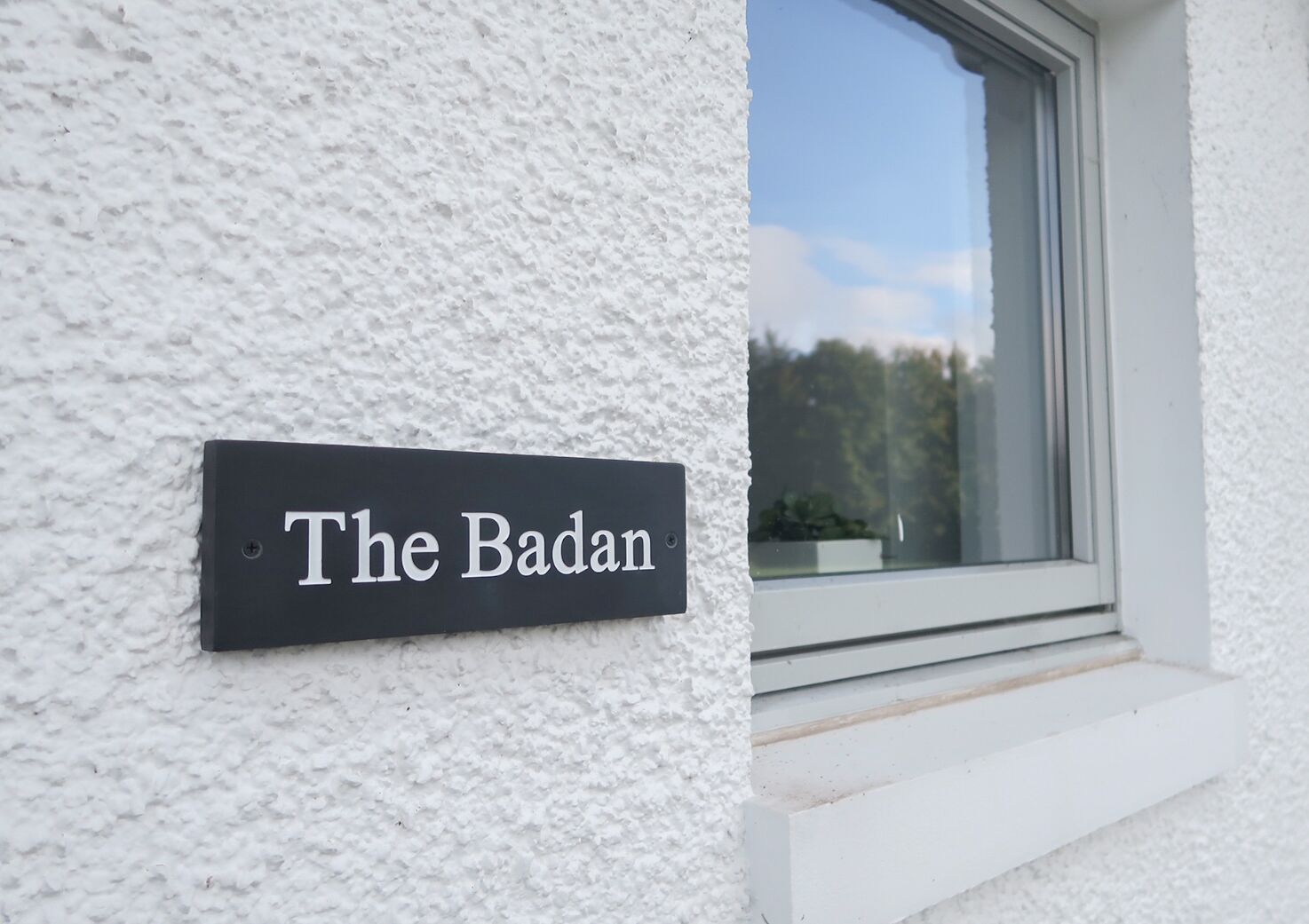 A sign on a textured white wall reading "The Badan."