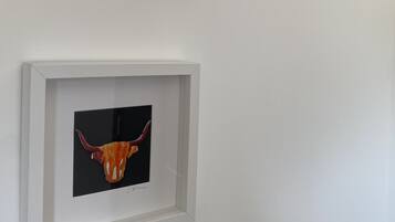 Una obra de arte enmarcada con la cabeza de un toro sobre una pared blanca.