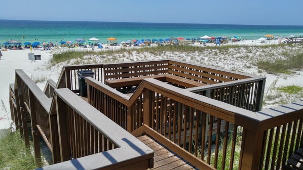 A wooden deck with a view of a beach and ocean. - Sand Pebbles #1401 Chateau La Mer II 2Bd-2Bath Walk-In Shower Ground Floor (Destin)