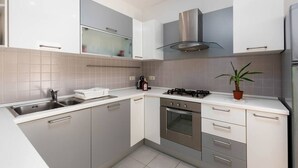 Eine moderne Küche mit Gasherd, Edelstahlgeräten und weißen Schränken.