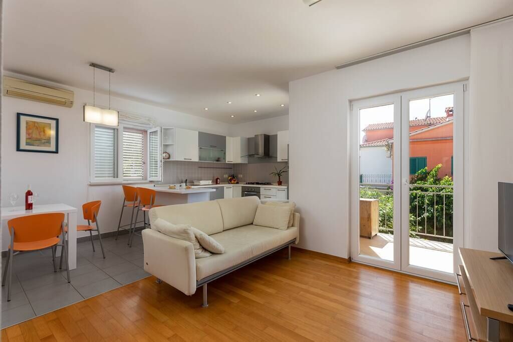 En moderne lejlighed med stue, spiseområde, køkken og en balkon med udsigt.