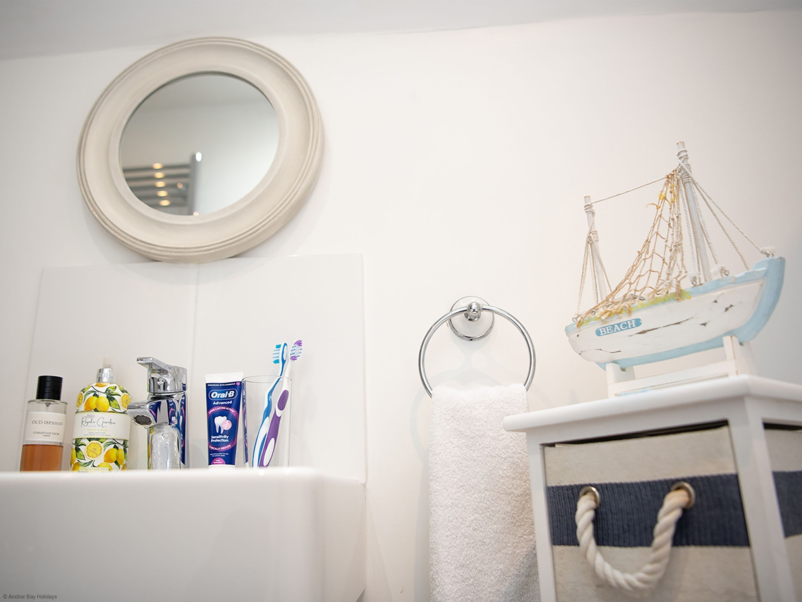 Un baño con lavamanos, cepillos de dientes y una decoración náutica colgante.