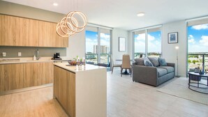 A modern apartment with a kitchen, dining area, and living room. It features large windows, a balcony, and a city view.