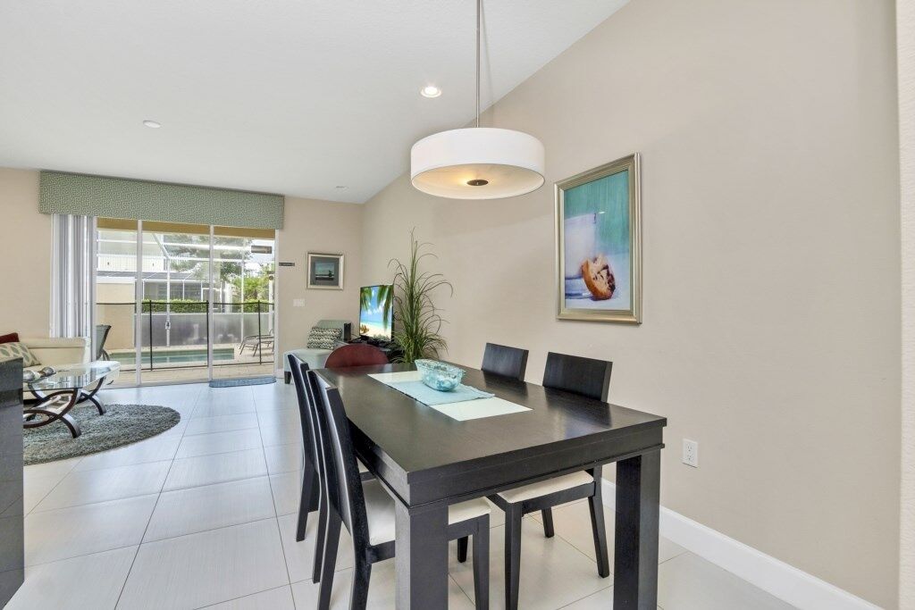 A modern dining area with a dark wooden table, black chairs, and a white pendant light.