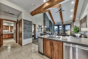 A modern kitchen with a large island, wooden beams, and a stone backsplash. - Luxury Two Bedroom Residence steps from Heavenly Village by RedAwning (South Lake Tahoe)