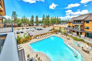 A pool area with lounge chairs and a clear blue pool, surrounded by buildings and trees. - Luxury Two Bedroom Residence steps from Heavenly Village by RedAwning (South Lake Tahoe)