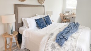 A neatly arranged bedroom with a bed, bedside tables, a desk, and a chair. - Charleston "Chucktown Cottage" mins to Beach (Mount Pleasant)