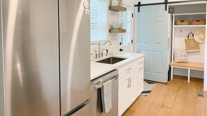 A modern kitchen with stainless steel appliances, a white countertop, and wooden flooring. - Charleston "Chucktown Cottage" mins to Beach (Mount Pleasant)