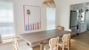 A modern kitchen with a wooden dining table, wicker chairs, and a hanging light fixture. - Charleston "Chucktown Cottage" mins to Beach (Mount Pleasant)