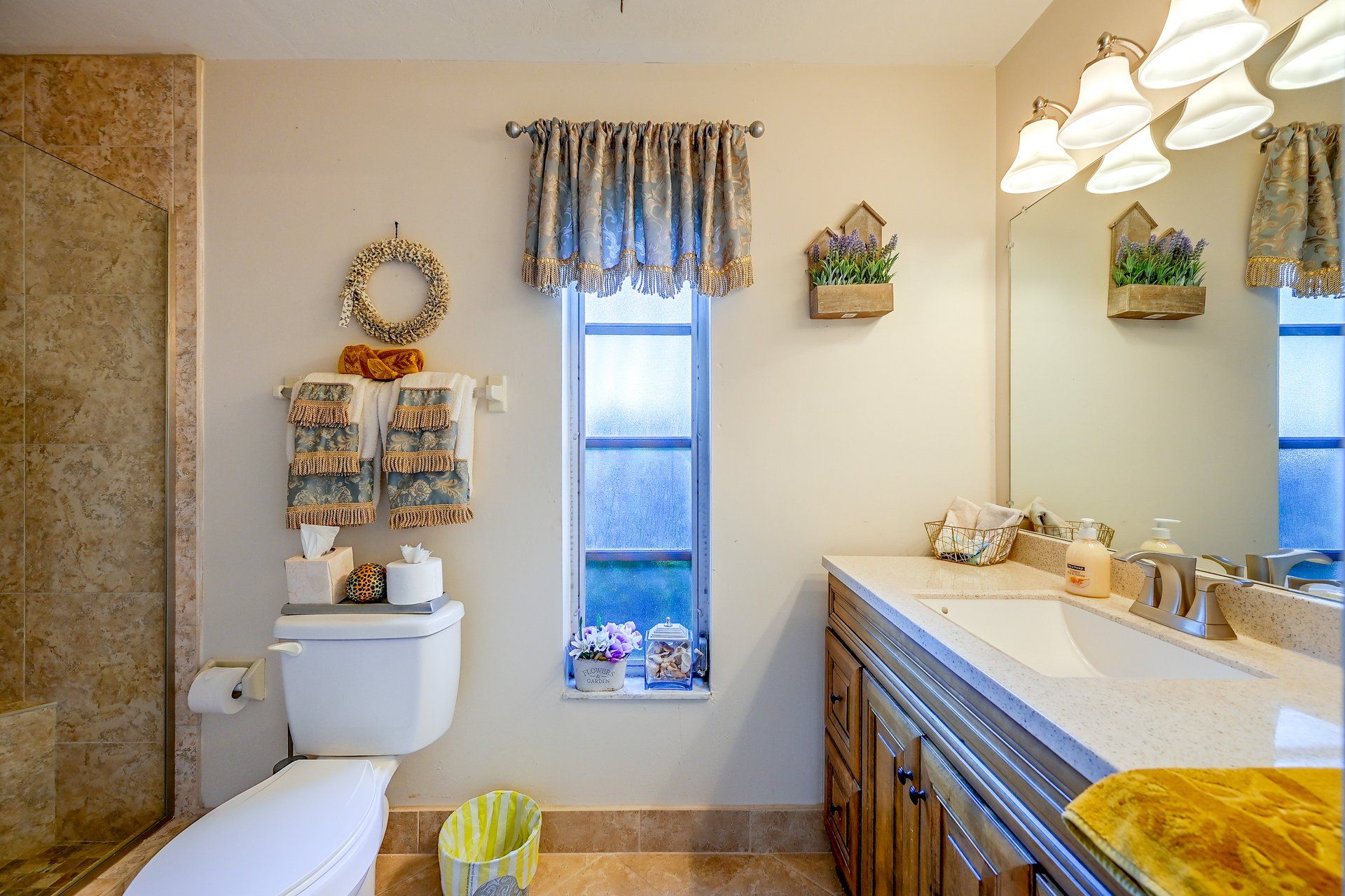 A bathroom with a toilet, a sink, a mirror, and a window with curtains.