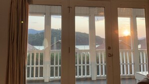 Une pièce dotée d’une grande porte-fenêtre coulissante donnant sur un balcon avec vue sur un lac et des montagnes.