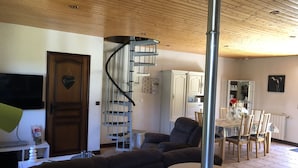Una sala de estar moderna con un sofá curvo, una escalera en espiral y un comedor con mesa y sillas.