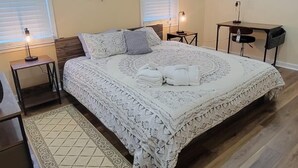 Un dormitorio con una cama grande, dos mesitas de noche, un buró, un escritorio y una silla.