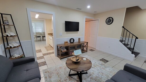 Una sala de estar con un sofá, una mesa de centro, un televisor y una escalera.